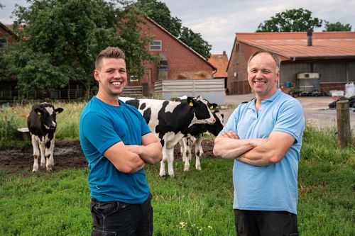 Jung und Seniorbauer stehen vor Kuhherde